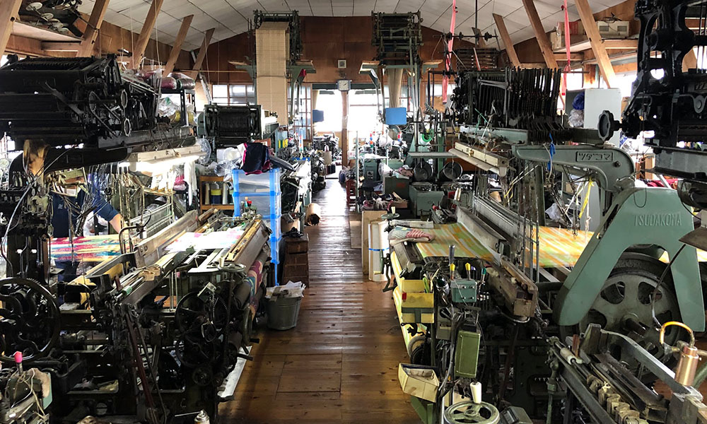 舟久保織物の工房内。９台の織機が並ぶ、圧巻の織場。
